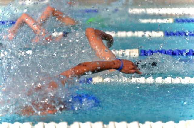 A slight motion blur gives a dramatic effect to this freestyle swim race. The water is splashing high as the swimmers fight for a lead in the race.
